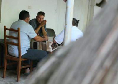 Zdjęcie przedstawia trzech rozmawiających przy stole mężczyzn.